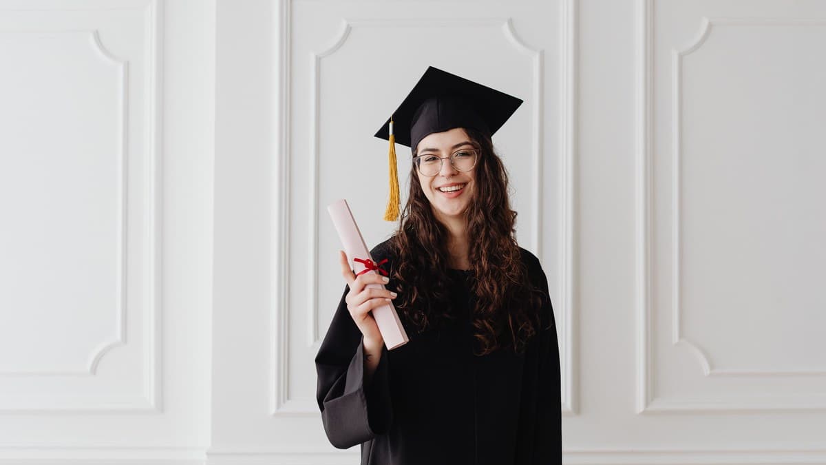 Lächelnde Absolventin mit Doktorhut und Diplom, Sinnbild für den Master of Laws (LL.M.)