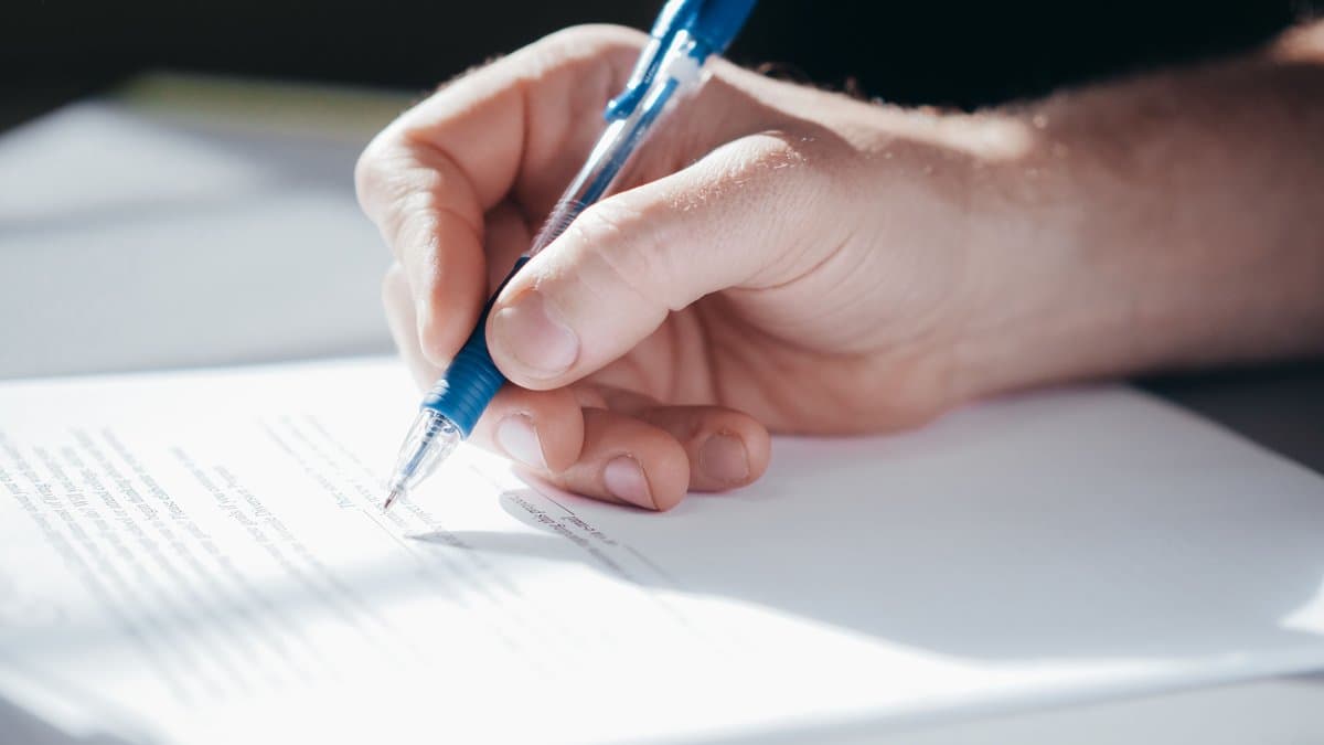 Hand unterschreibt ein Dokument als Sinnbild für den Vertragsschluss und die essentialia negotii