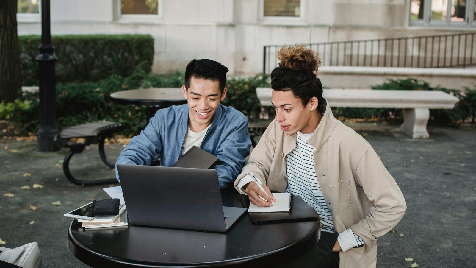 Studierende sitzen auf Stufen vor einem Gebäude, Sinnbild für den Studienstart im Jurastudium