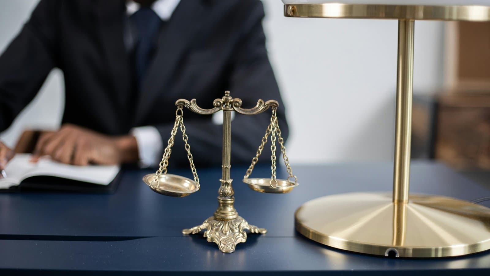 Justitia-Waage neben Büchern, Sinnbild für Normen und Rechtsnormen