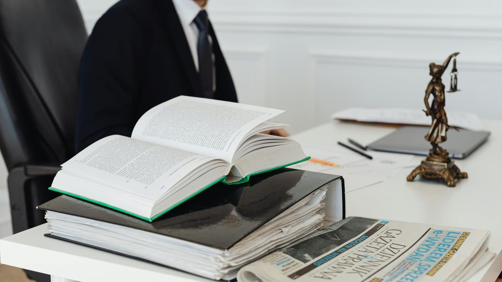 Aufgeschlagenes Buch mit Justitia-Figur, Sinnbild für den Ablauf des juristischen Referendariats
