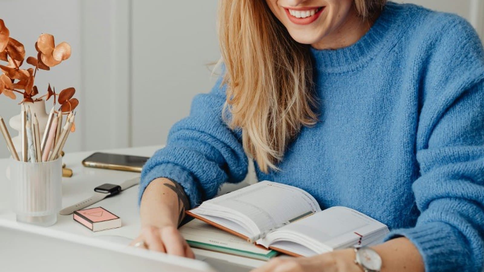 Lächelnde Studentin macht sich Notizen am Schreibtisch, Sinnbild für das beste Jura-Fallbuch und Falltraining