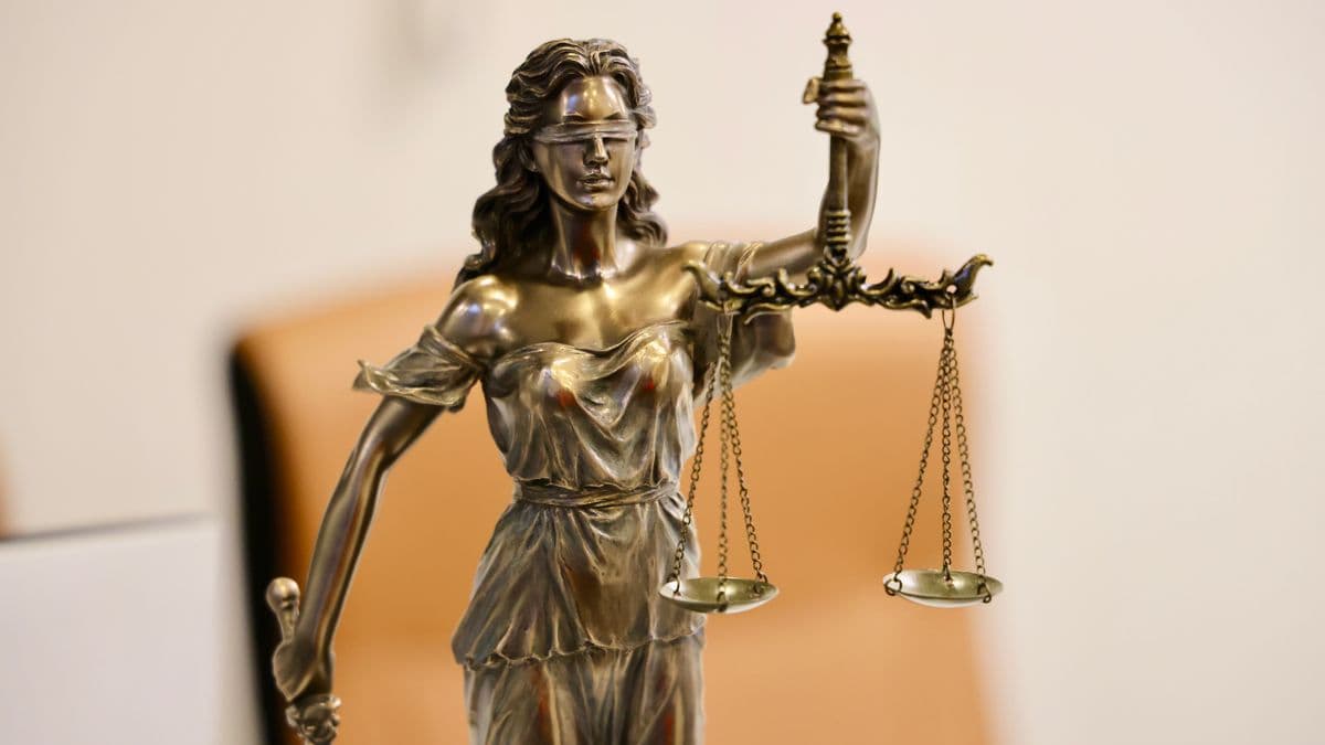 Bronzestatue der Justitia mit verbundenen Augen, einer Waage und einem Schwert.