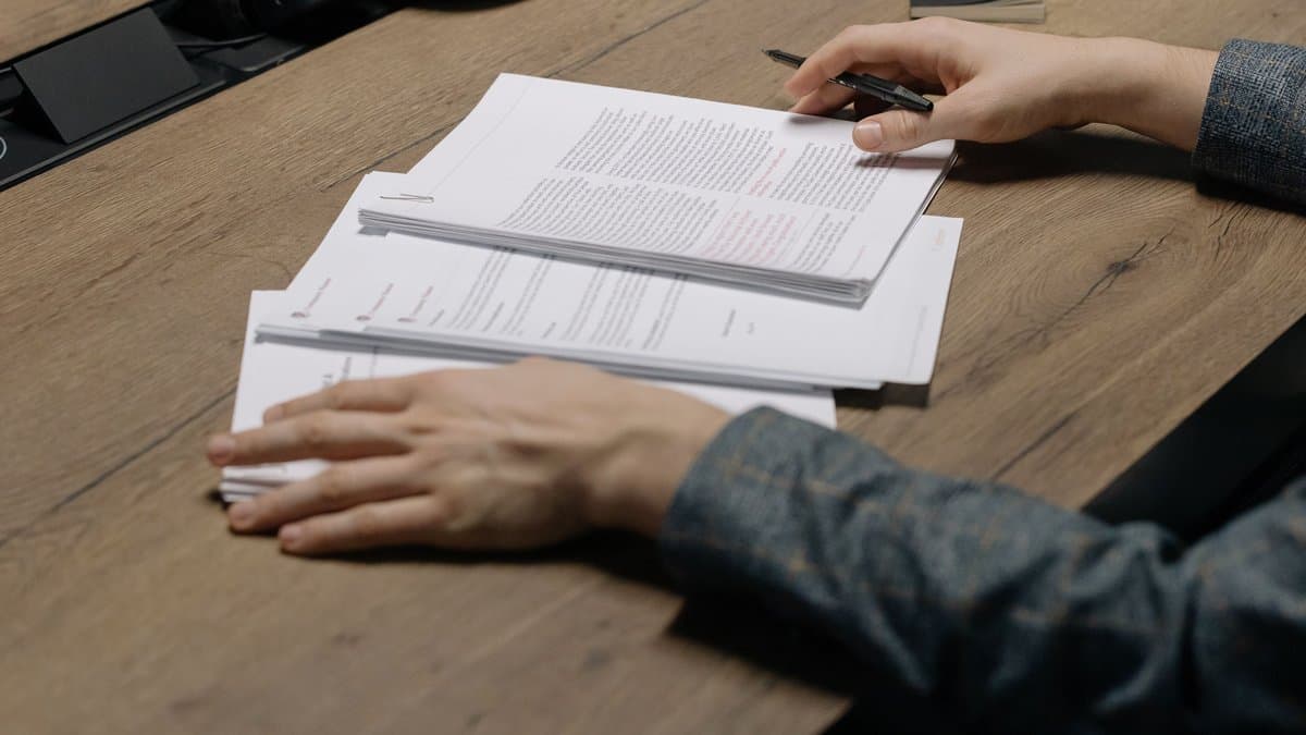 Hände korrigieren einen ausgedruckten Lernzettel mit Rotstift, Sinnbild für das Überarbeiten einer Jura-Zusammenfassung
