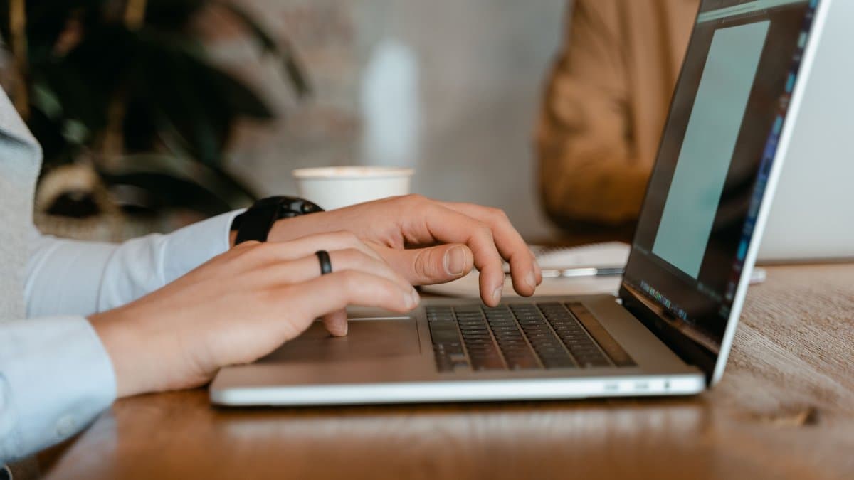 Hände tippen auf einer Laptop-Tastatur im Büro beim Schreiben einer Hausarbeit