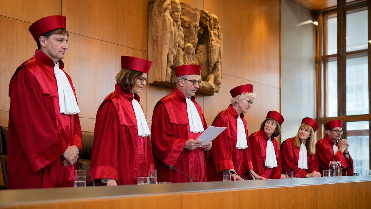 Richterinnen und Richter in roter Robe an der Richterbank im Sitzungssaal eines Verfassungsgerichts