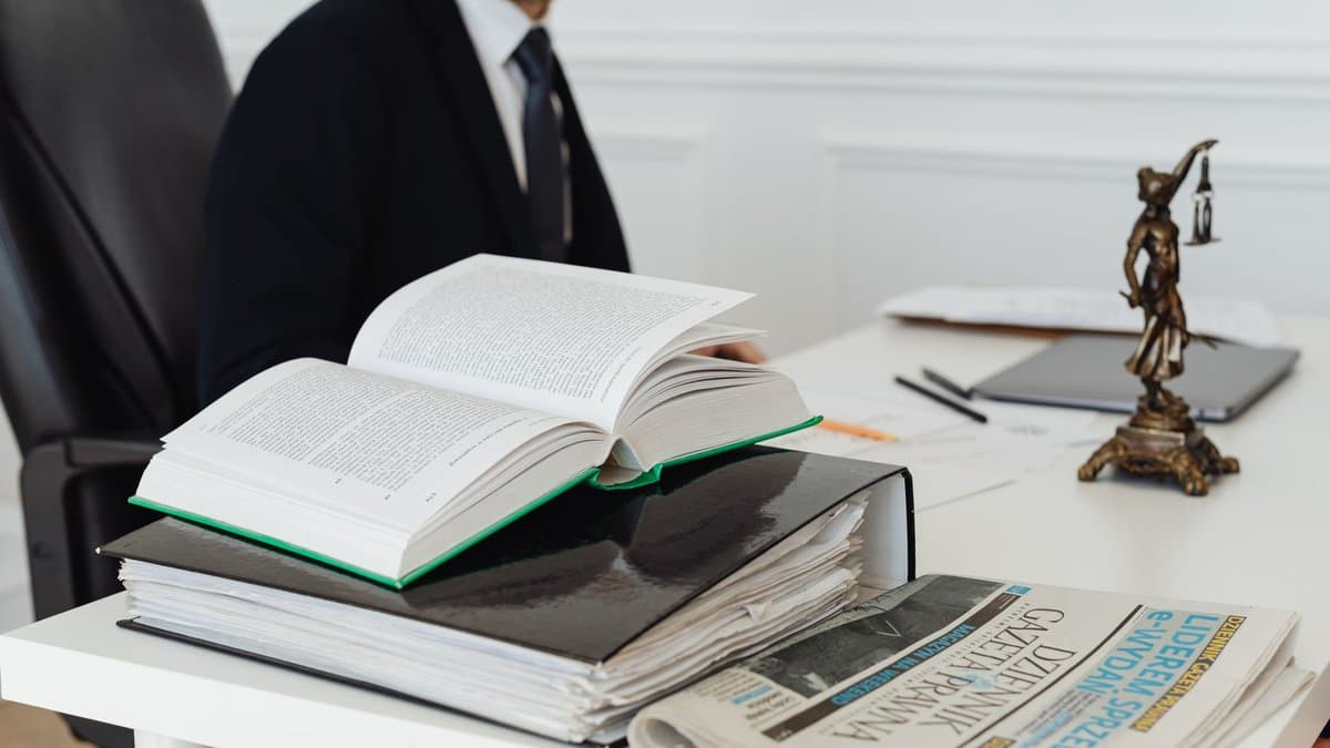 Aufgeschlagenes Gesetzbuch auf einem Bücherstapel an einem Schreibtisch
