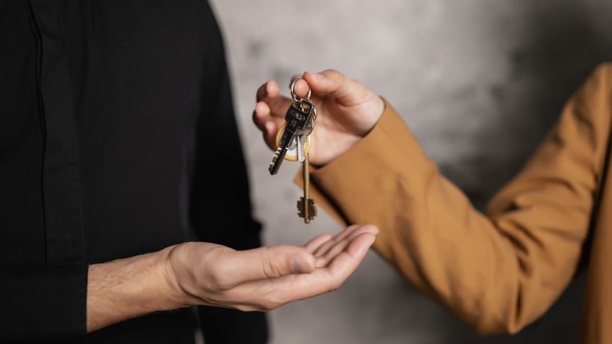 Eine Hand lässt einen Schlüsselbund in die offene Handfläche einer zweiten Person fallen