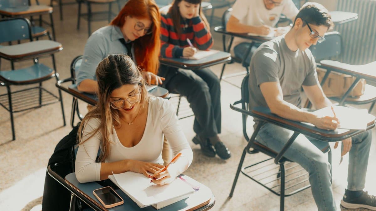 Studierende sitzen im sonnendurchfluteten Hörsaal über ihren Klausuren