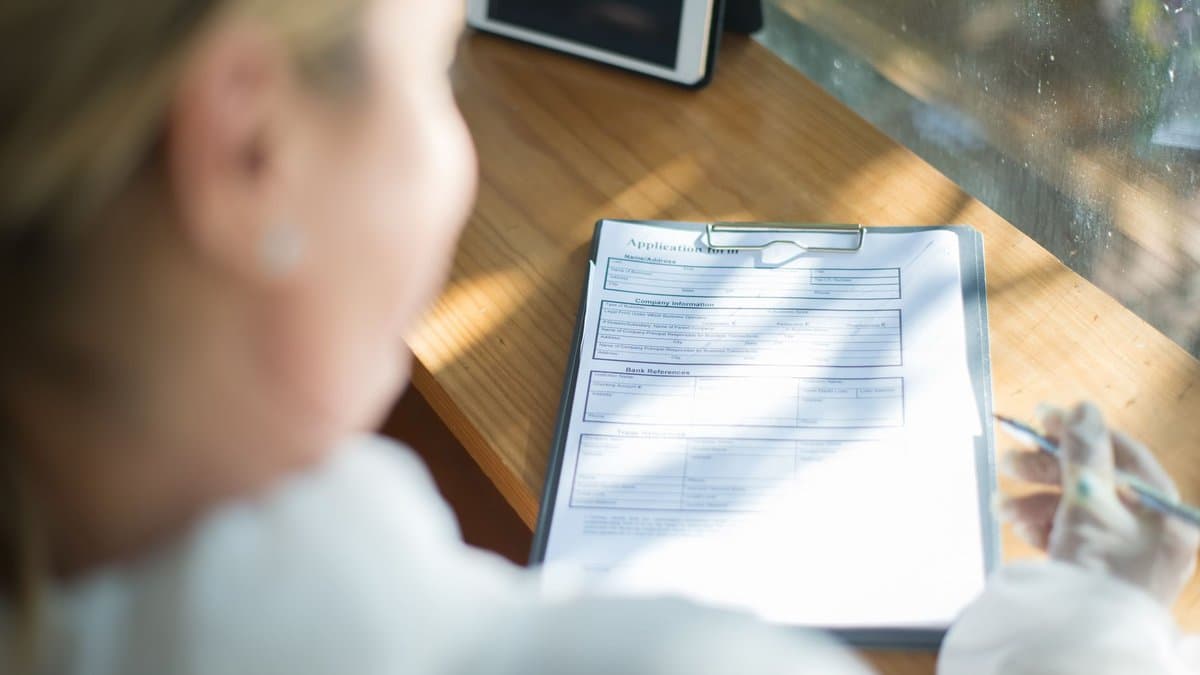 Studentin füllt an einem sonnigen Schreibtisch ein Antragsformular aus
