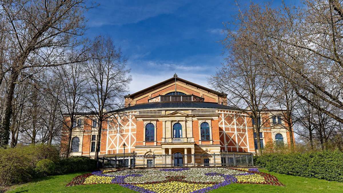 Das Bayreuther Festspielhaus hinter einem bepflanzten Blumenbeet an einem sonnigen Frühlingstag