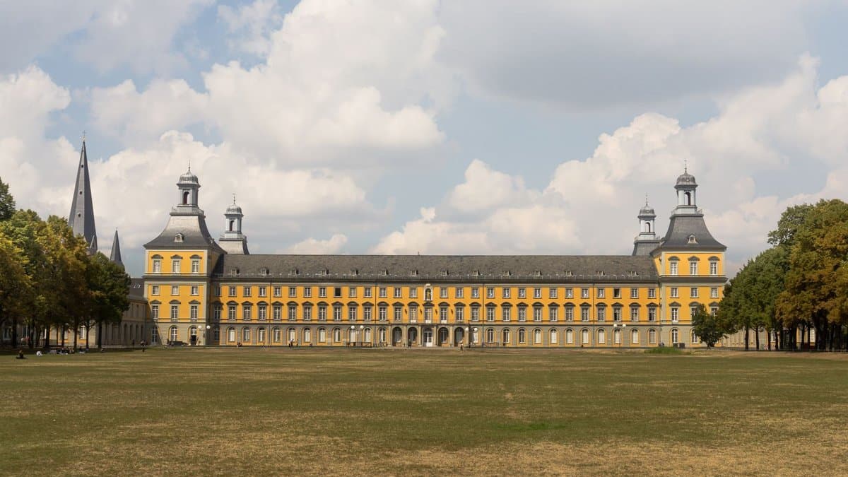Das Kurfürstliche Schloss der Universität Bonn vom Hofgarten aus, gelbe Barockfassade unter Sommerhimmel