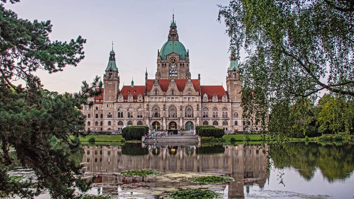 Das Neue Rathaus von Hannover spiegelt sich im Maschteich, umrahmt von Bäumen