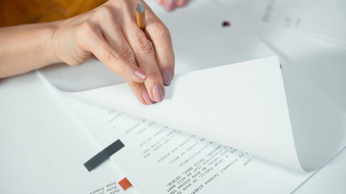 Hand blättert mit einem Stift in den ausgedruckten Seiten einer Arbeit
