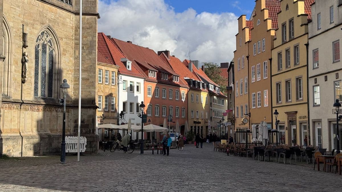 Marktplatz der Osnabrücker Altstadt mit bunten Giebelhäusern, Kopfsteinpflaster und Außentischen vor den Lokalen