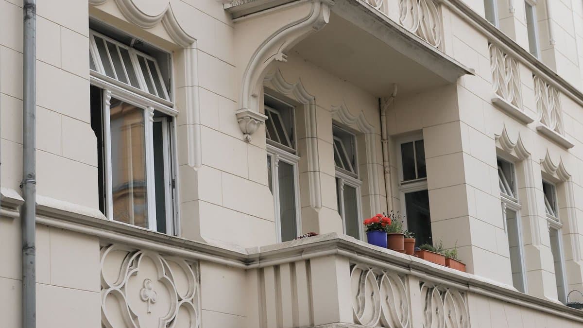 Altbaufassade mit Erker, Balkon und Blumentöpfen an einem Wohnhaus