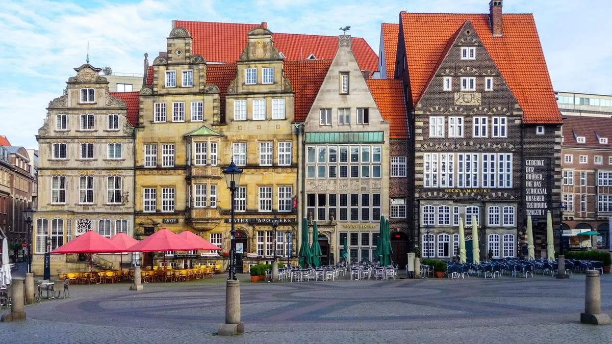 Giebelhäuser am Bremer Marktplatz unter blauem Himmel, davor Cafétische