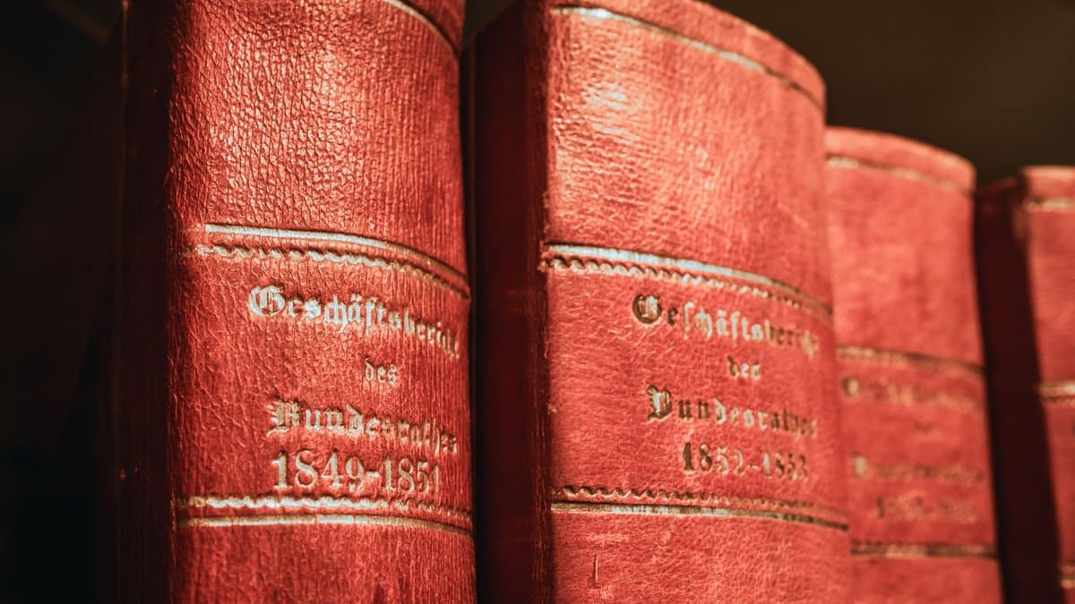 Reihe alter rot eingebundener Gesetzesbände mit goldgeprägten Rücken in einem Bibliotheksregal