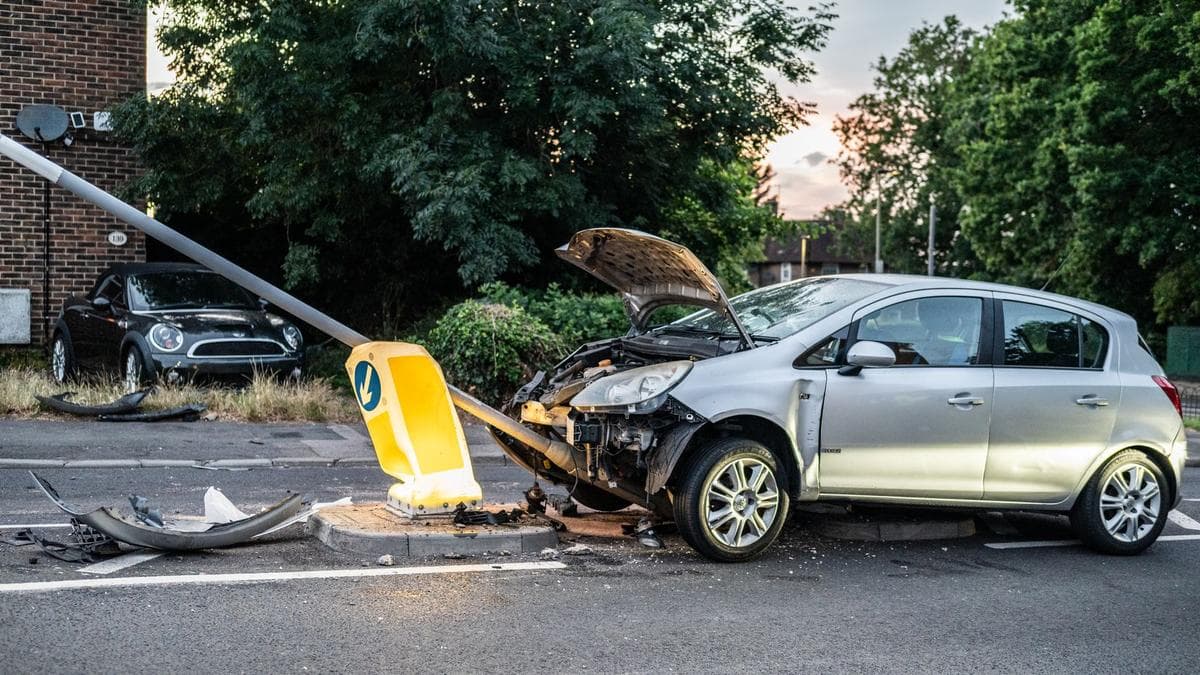 Silbernes Auto mit zerstörter Front nach dem Zusammenstoß mit einem umgeknickten Laternenmast