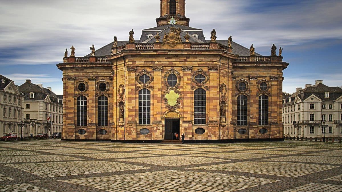 Die barocke Ludwigskirche in Saarbrücken auf dem gepflasterten Ludwigsplatz unter bewölktem Himmel