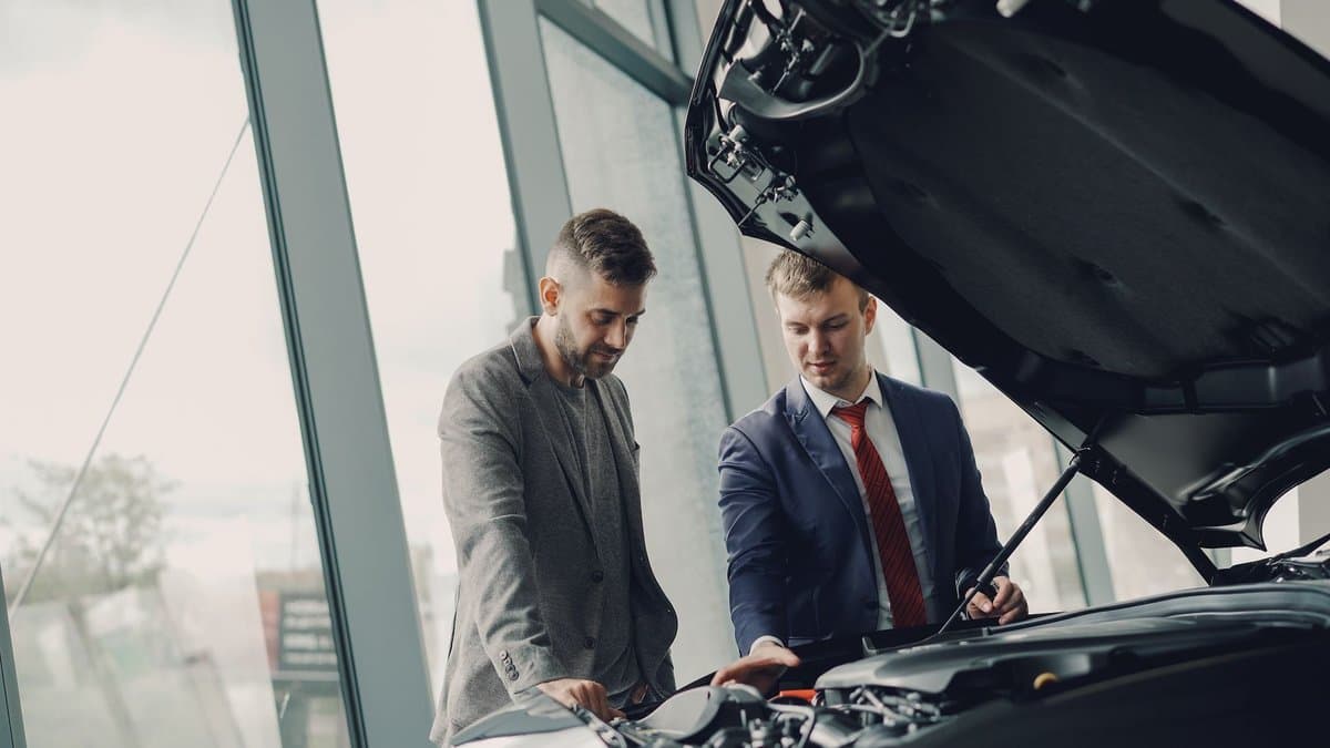 Zwei Männer schauen im Autohaus unter die geöffnete Motorhaube eines Autos