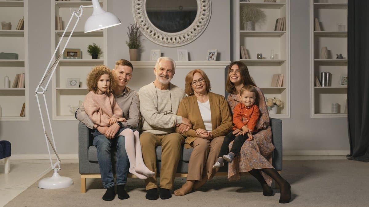 Drei Generationen einer Familie sitzen nebeneinander auf einem Sofa im Wohnzimmer