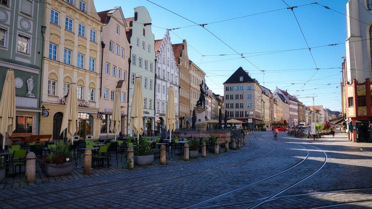 Die Augsburger Maximilianstraße mit Brunnen, Giebelhäusern und Straßenbahngleisen am Morgen