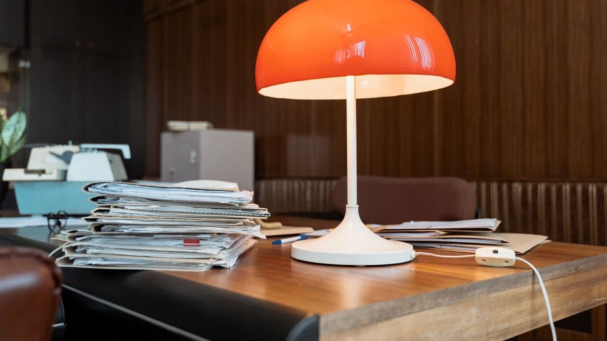 Schreibtisch mit einem Stapel Unterlagen und einer Tischlampe in einem Büro