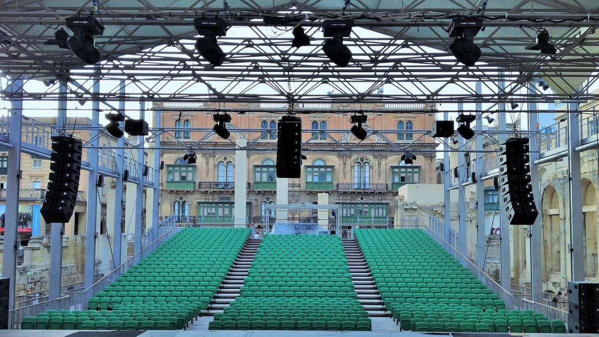 Leere Sitzreihen vor einer aufgebauten Bühne mit Licht- und Tontechnik, kein Publikum im Saal