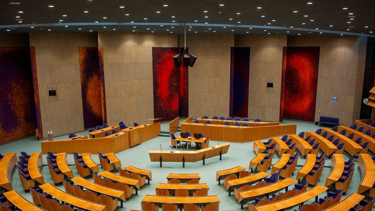 Leerer Plenarsaal eines Parlaments mit halbrunden Sitzreihen, Blick von der Besuchertribüne