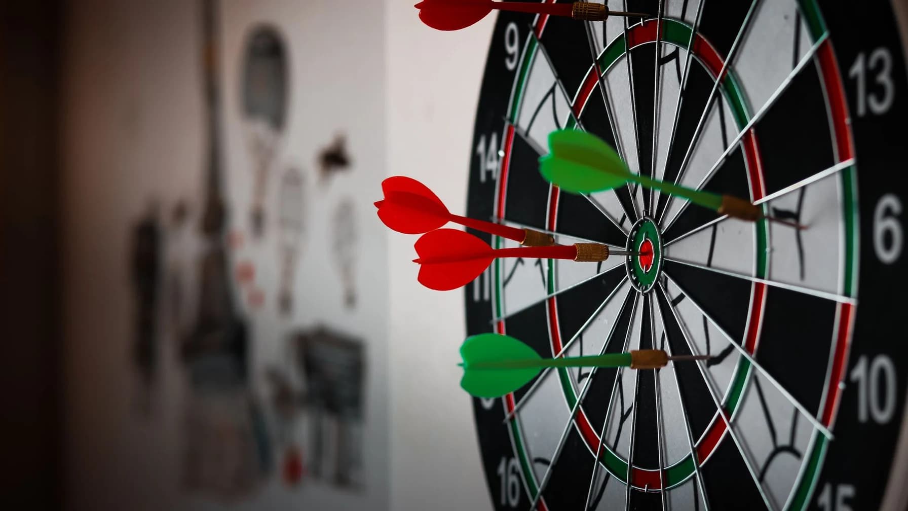 Mehrere Wurfpfeile stecken verstreut in unterschiedlichen Feldern einer Dartscheibe, nicht alle in der Mitte