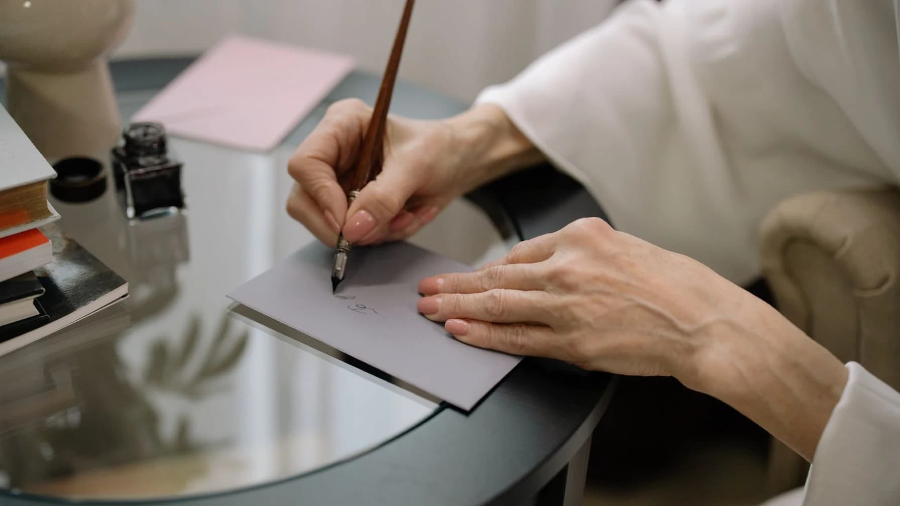 Hand schreibt mit einem Füllfederhalter auf einem Briefumschlag