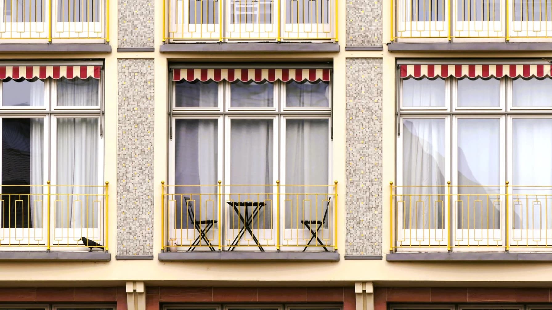Altbau-Wohnhaus mit Balkonen und roten Markisen an einer Straße