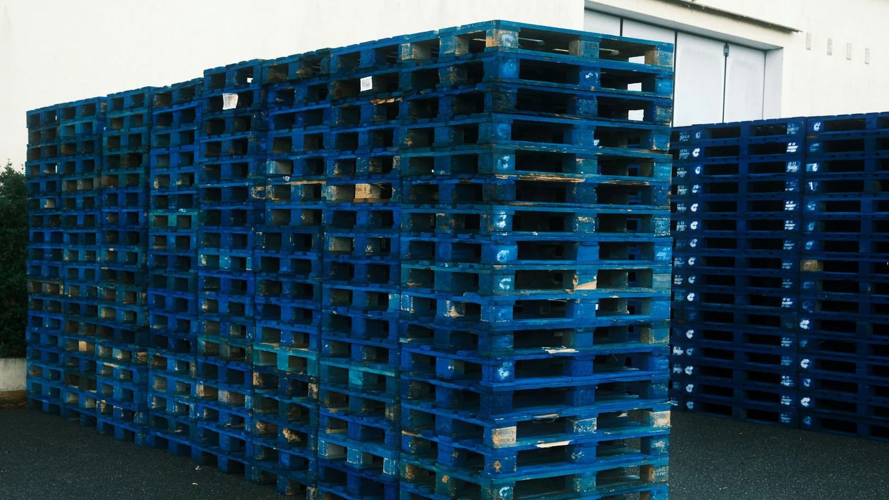 Blau gestapelte Paletten vor einem Lagergebäude